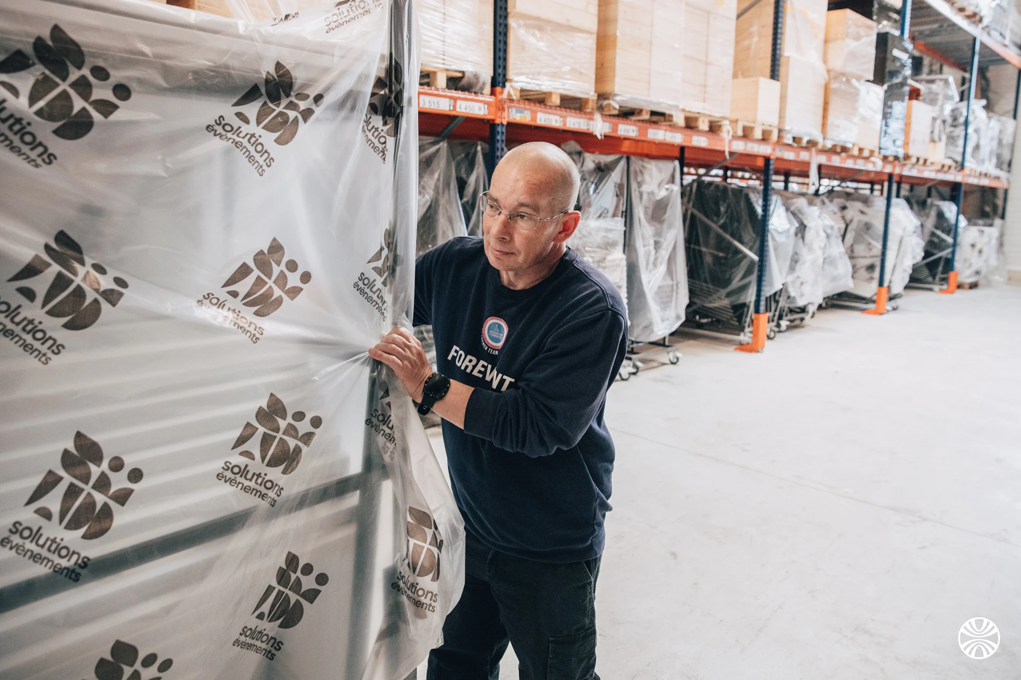 Préparateur protégeant un chariot de mobilier sous film dans l'entrepôt de stockage Solutions Événements